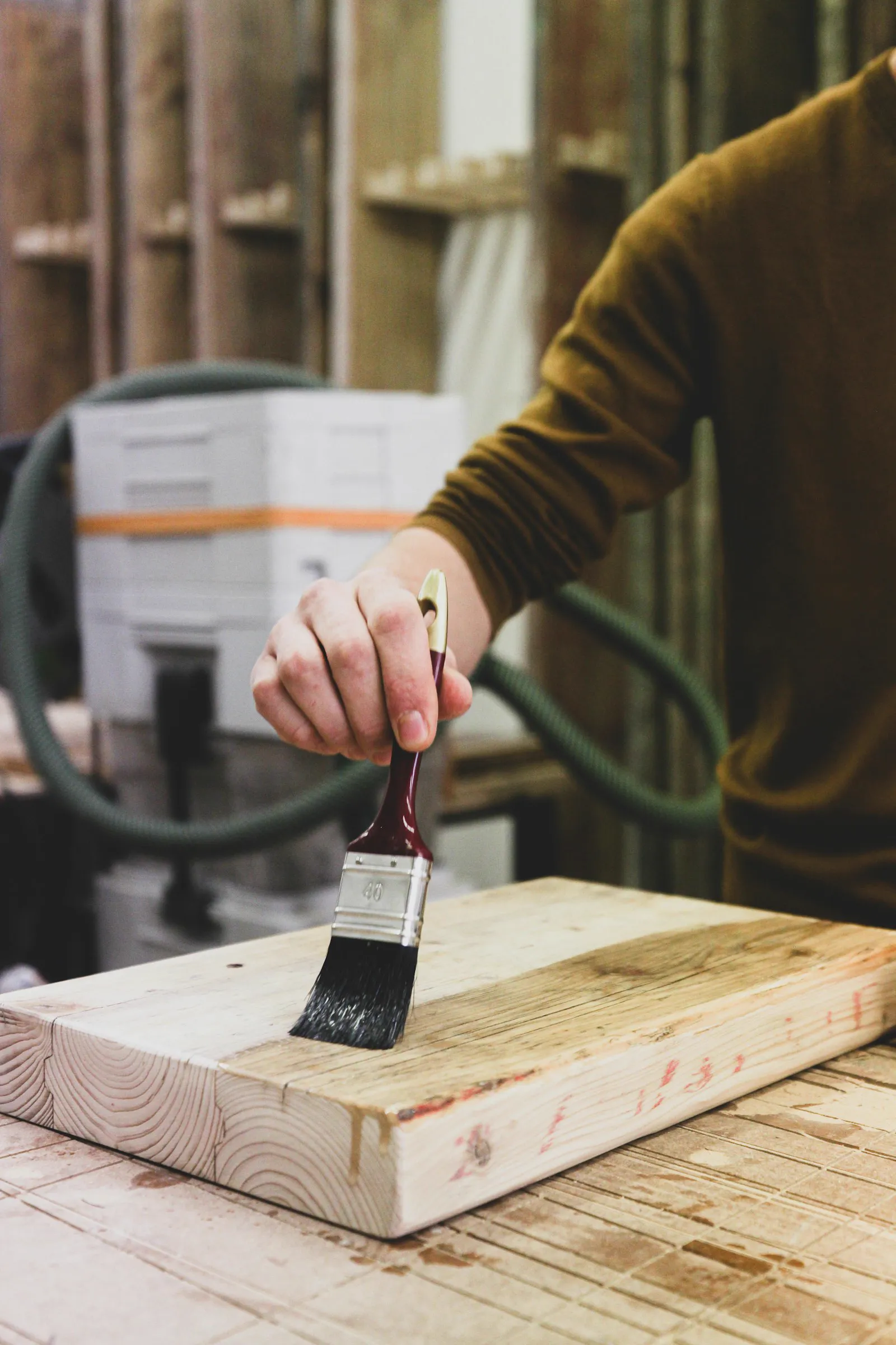 Hand applying finish to wood with a paintbrush