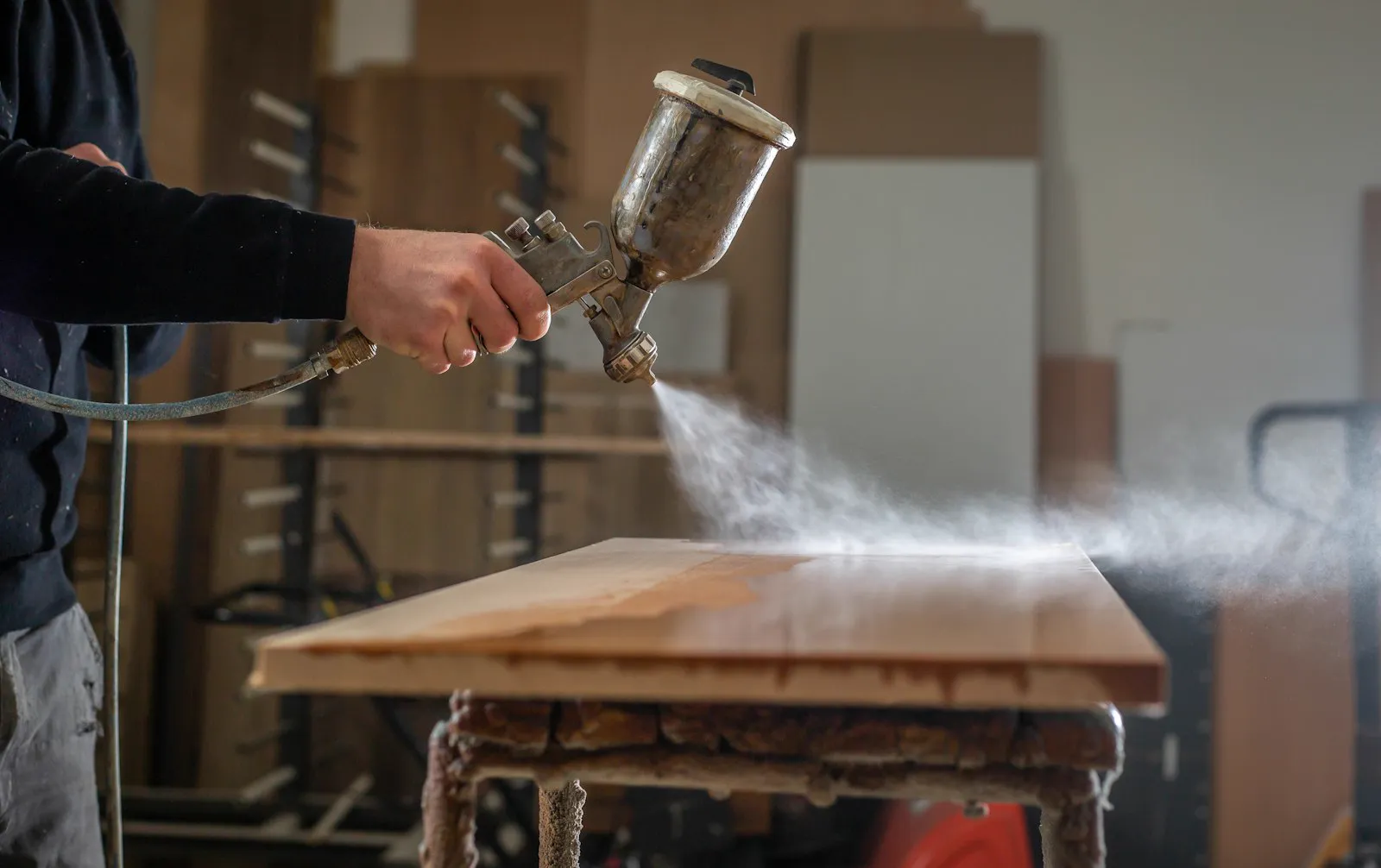 Craftsperson applying a finish to a wooden tabletop in the workshop